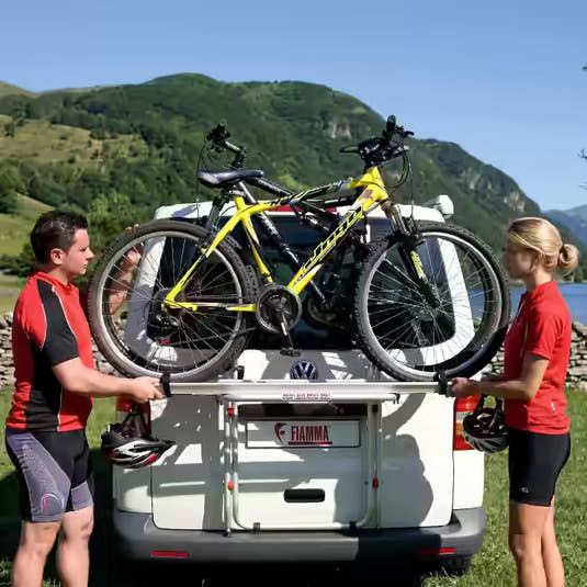 Couple standing beside bikes on a campervan-mounted bicycle carrying rack