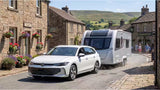 Volkswagen Passat B9 Estate car towing a caravan through an English village