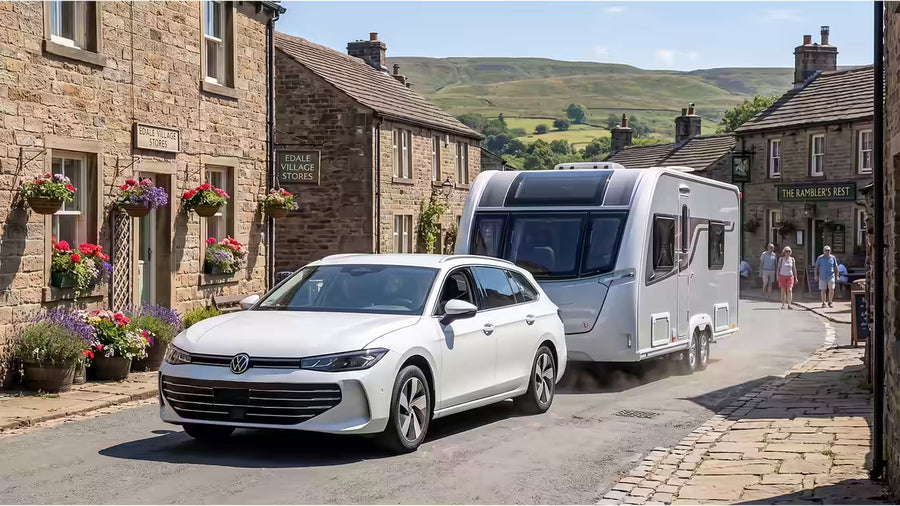 Volkswagen Passat B9 Estate car towing a caravan through an English village