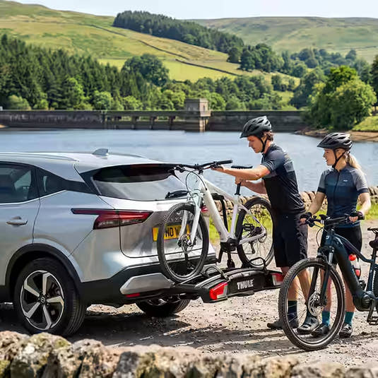 E-bikes being loaded onto a Thule bike rack in a scenic lakeside car park