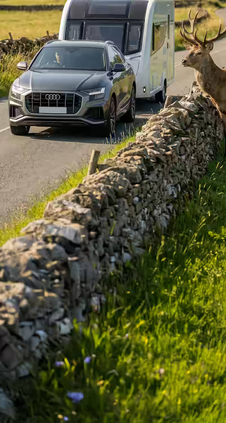 Audi car towing a caravan along a country lane