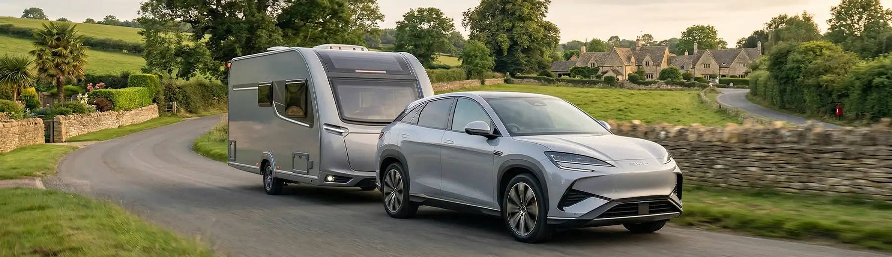 BYD car towing a modern caravan through an English village