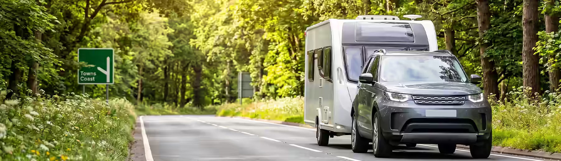 Grey Land Rover SUV towing a caravan along a British A-road